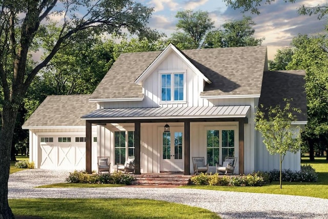 modern inspired farmhouse with a porch, an attached garage, gravel driveway, board and batten siding, and a standing seam roof