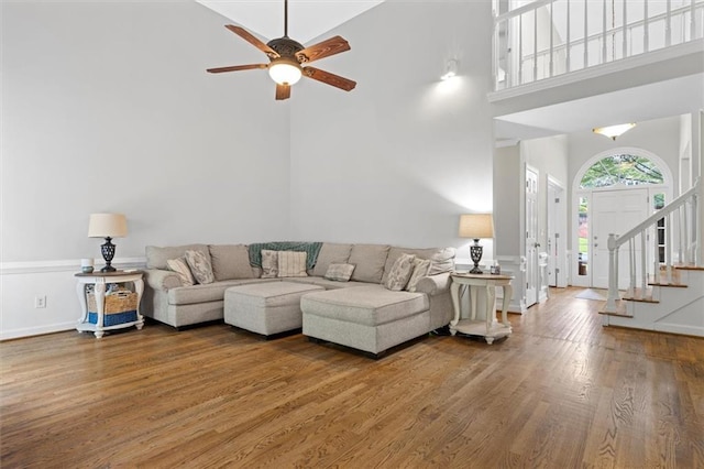 4381 Laurian Dr NW, Kennesaw, GA 30144 - living room featuring a towering ceiling, wood finished floors, a ceiling fan, stairs, and baseboards