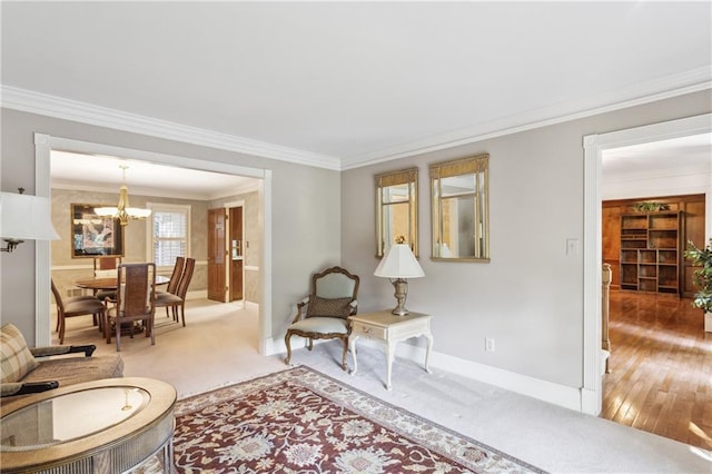 living area with crown molding, a chandelier, baseboards, light colored carpet, and light wood-style floors