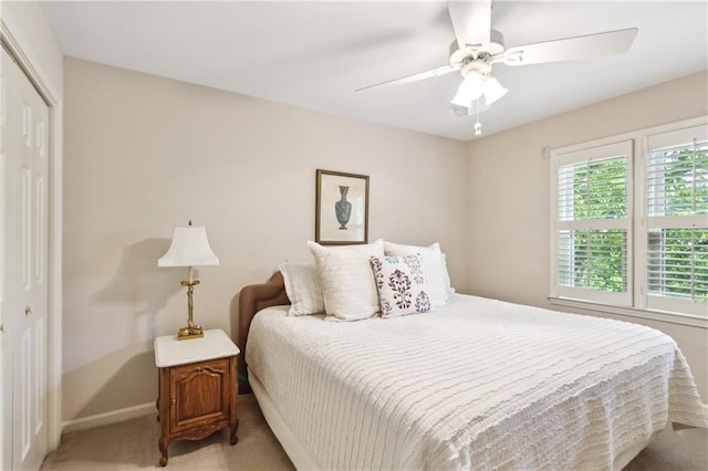 bedroom featuring light colored carpet, a closet, baseboards, and ceiling fan