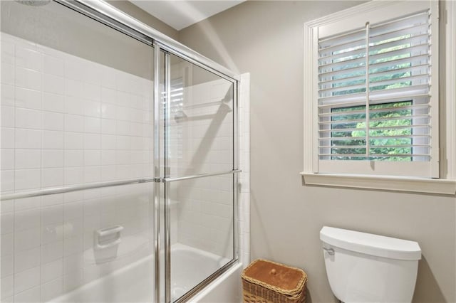 bathroom featuring bath / shower combo with glass door and toilet
