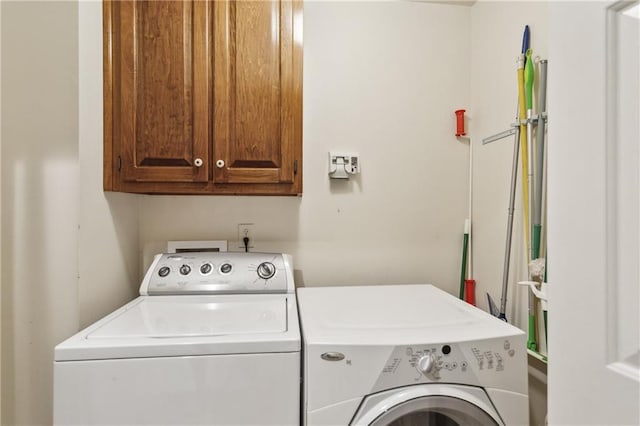 clothes washing area featuring washing machine and dryer and cabinet space
