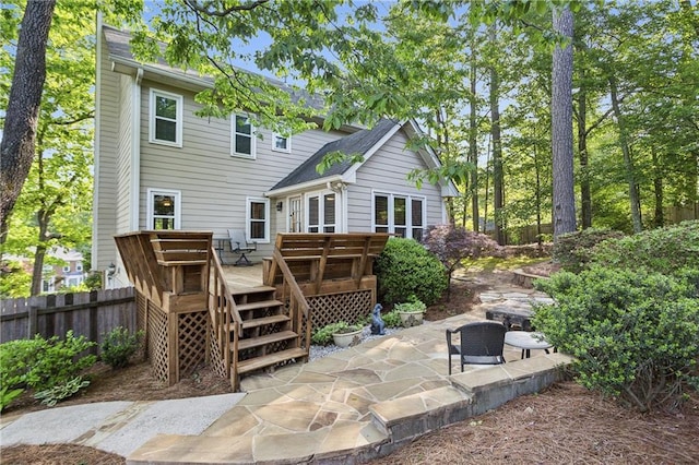 rear view of property featuring a wooden deck, fence, and a patio