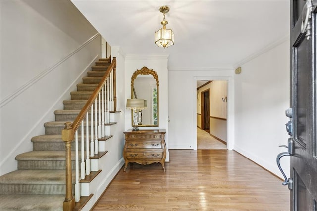 entryway featuring stairs, light wood-style floors, ornamental molding, and baseboards