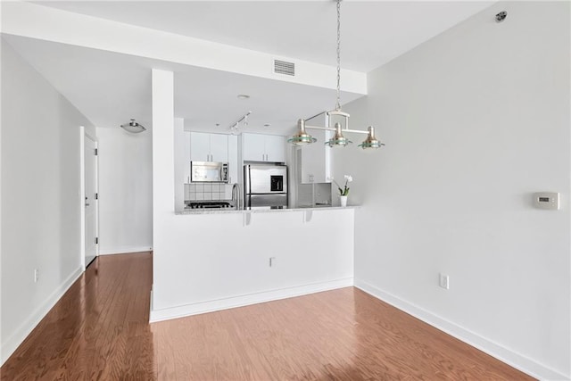 unfurnished living room featuring a notable chandelier, sink, and hardwood / wood-style flooring