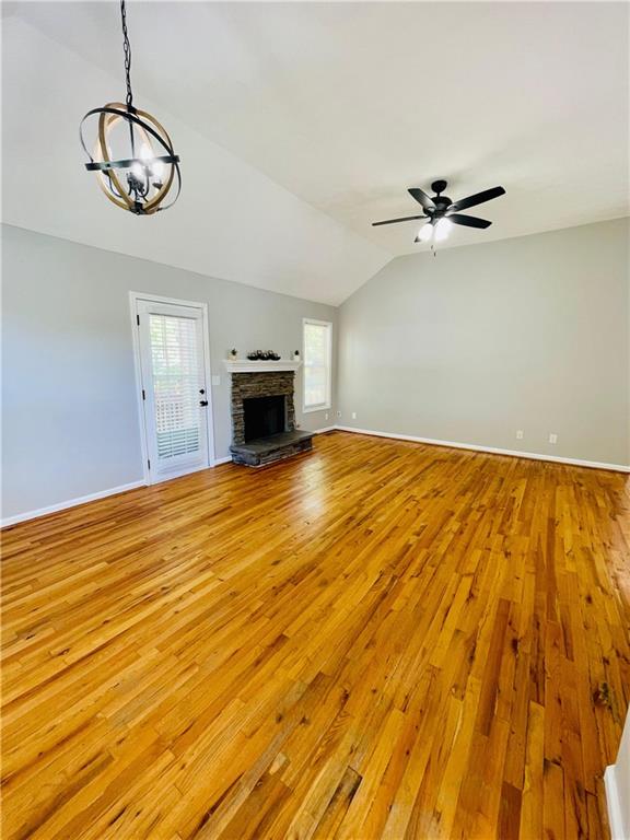 350 Fall View Ct, Winder, GA 30680 - unfurnished living room with light wood-type flooring, vaulted ceiling, baseboards, a chandelier, and plenty of natural light