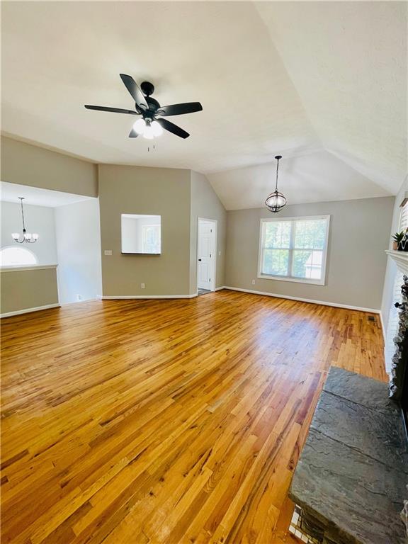350 Fall View Ct, Winder, GA 30680 - unfurnished living room featuring light wood-style floors, a chandelier, a ceiling fan, lofted ceiling, and baseboards