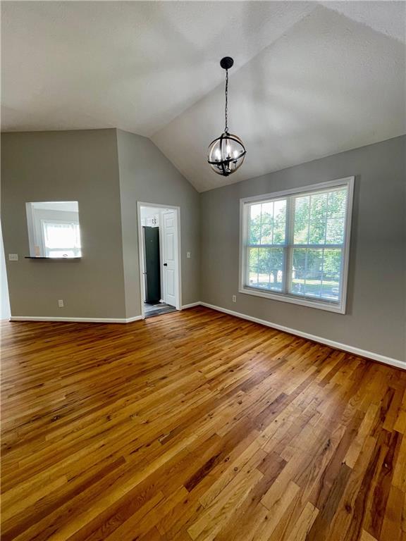350 Fall View Ct, Winder, GA 30680 - spare room with hardwood / wood-style floors, a chandelier, lofted ceiling, and baseboards