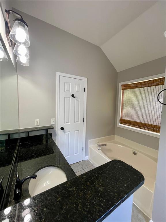 350 Fall View Ct, Winder, GA 30680 - bathroom with a garden tub, vaulted ceiling, tile patterned floors, and vanity