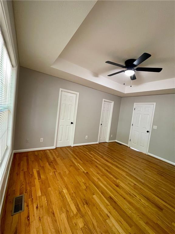 350 Fall View Ct, Winder, GA 30680 - empty room with a raised ceiling, light wood finished floors, baseboards, and a ceiling fan