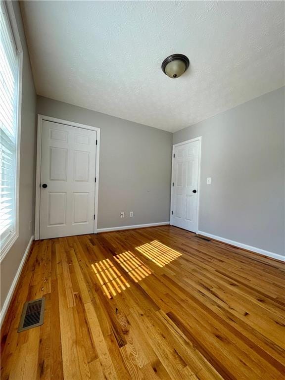 350 Fall View Ct, Winder, GA 30680 - unfurnished bedroom featuring light wood-type flooring, baseboards, and a textured ceiling