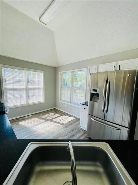 350 Fall View Ct, Winder, GA 30680 - kitchen featuring stainless steel refrigerator with ice dispenser, vaulted ceiling, white cabinets, dark countertops, and wood finished floors