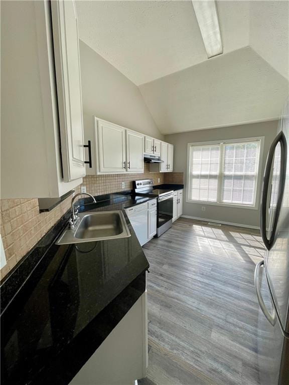350 Fall View Ct, Winder, GA 30680 - kitchen featuring stainless steel appliances, a sink, dark countertops, white cabinets, and lofted ceiling