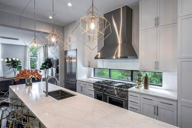 kitchen with sink, wall chimney exhaust hood, decorative light fixtures, a breakfast bar, and high end appliances