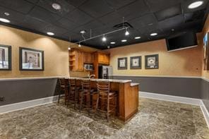 bar with track lighting, stainless steel microwave, fridge, and baseboards