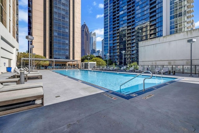 pool with a patio area, a view of city, and fence