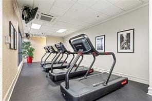 exercise room with a paneled ceiling, visible vents, and baseboards