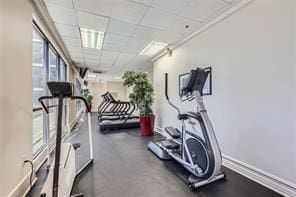 exercise area with a paneled ceiling and baseboards