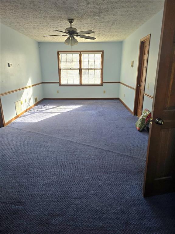 carpeted empty room with a textured ceiling and ceiling fan