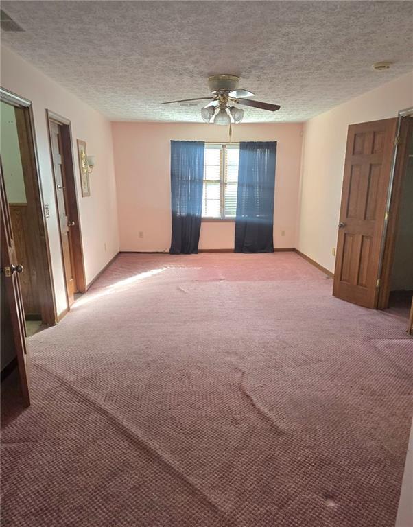 carpeted spare room featuring ceiling fan and a textured ceiling