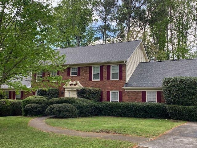 colonial home with a front yard and brick siding