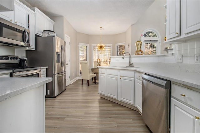 kitchen featuring a sink, appliances with stainless steel finishes, white cabinetry, tasteful backsplash, and light wood-type flooring