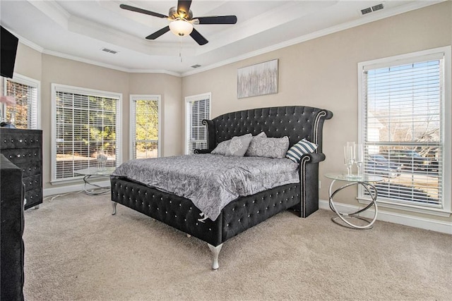 carpeted bedroom with visible vents, a raised ceiling, and multiple windows