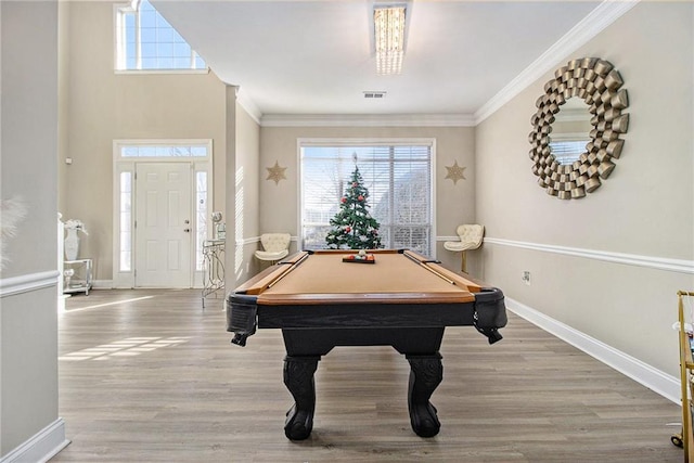 game room with crown molding, wood finished floors, a healthy amount of sunlight, and visible vents