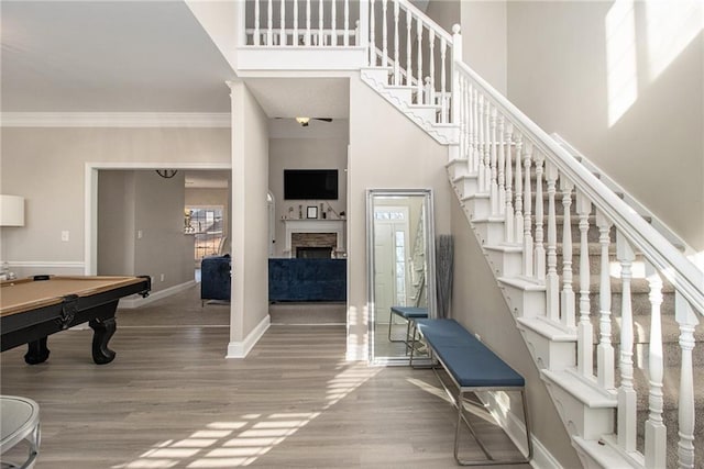 stairs with a high ceiling, a healthy amount of sunlight, wood finished floors, and ornamental molding