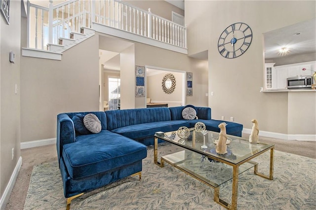 carpeted living area featuring a high ceiling and baseboards