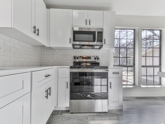 kitchen with decorative backsplash, a healthy amount of sunlight, white cabinetry, and stainless steel appliances