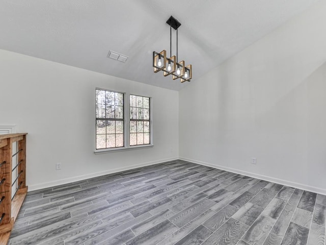 unfurnished dining area with hardwood / wood-style floors, an inviting chandelier, and lofted ceiling