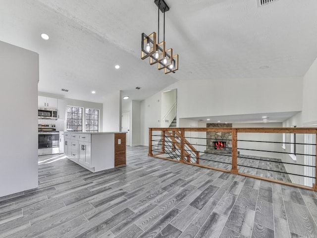 kitchen with a center island, light hardwood / wood-style floors, decorative light fixtures, white cabinets, and range