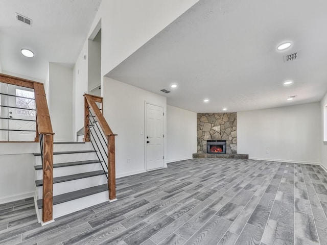 unfurnished living room featuring wood-type flooring and a stone fireplace