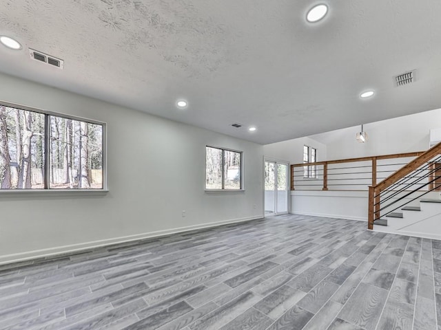 unfurnished living room featuring a textured ceiling and light hardwood / wood-style floors