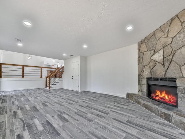 unfurnished living room featuring a fireplace, a textured ceiling, and hardwood / wood-style flooring