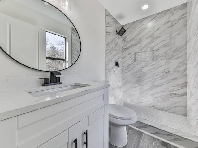 bathroom featuring toilet, vanity, and tiled shower