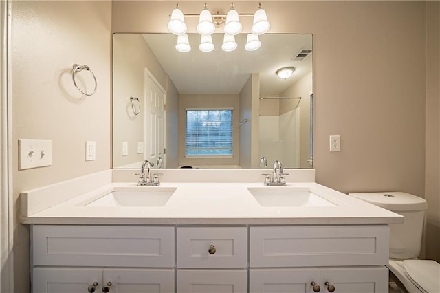 full bath featuring a stall shower, a sink, toilet, and double vanity