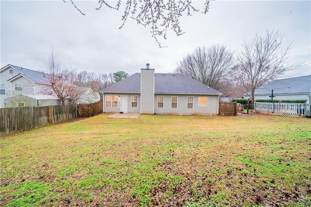 back of property featuring a yard, a chimney, a patio, and a fenced backyard