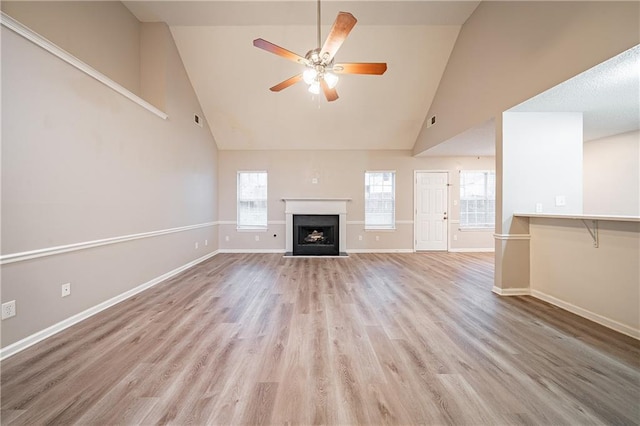 unfurnished living room featuring high vaulted ceiling, light wood-type flooring, ceiling fan, and baseboards