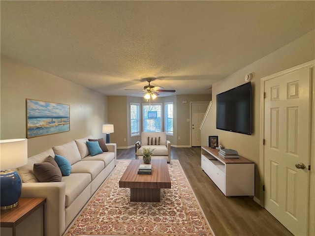 living room featuring ceiling fan, dark hardwood / wood-style flooring, and a textured ceiling