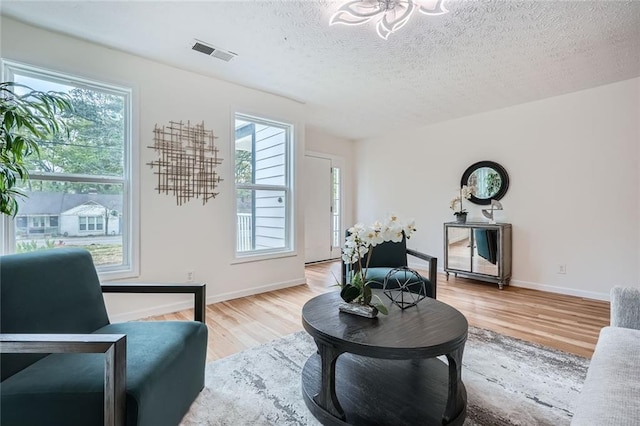 living area featuring wood finished floors, a textured ceiling, and baseboards