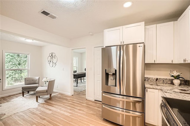 kitchen featuring stainless steel fridge with ice dispenser, light wood finished floors, white cabinetry, light stone counters, and baseboards