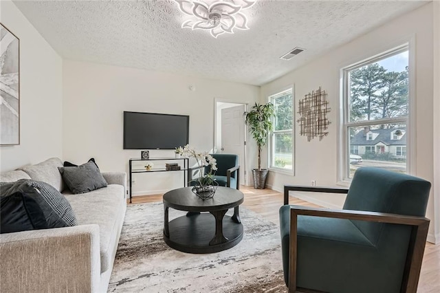 living area featuring a textured ceiling, light wood-style flooring, and a chandelier