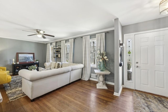 living area featuring a ceiling fan, visible vents, baseboards, and wood finished floors