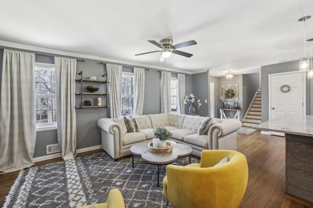 living area featuring baseboards, visible vents, ceiling fan, stairway, and wood finished floors