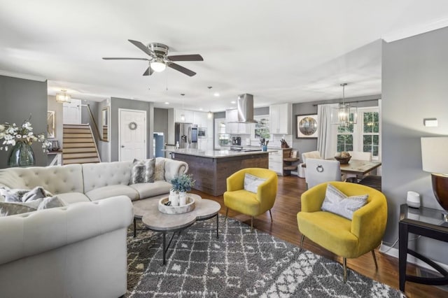 living area featuring dark wood-style floors, stairway, and ceiling fan with notable chandelier