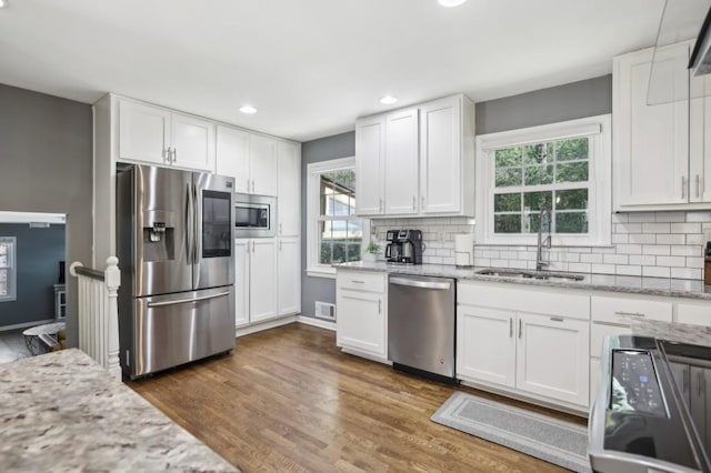 kitchen featuring tasteful backsplash, appliances with stainless steel finishes, dark wood-type flooring, white cabinetry, and a sink