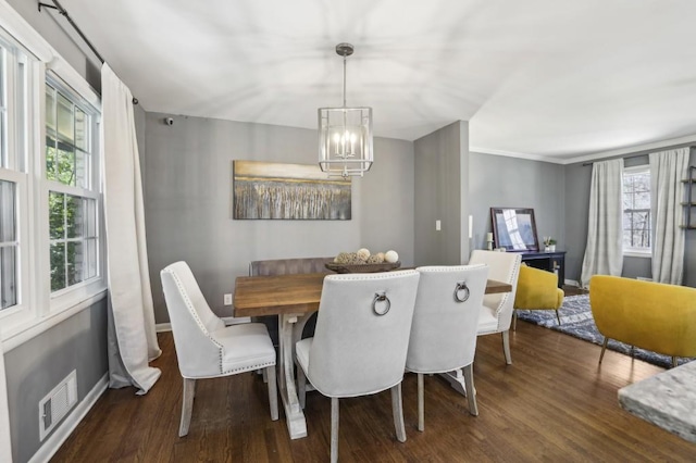 dining space featuring baseboards, visible vents, a chandelier, and wood finished floors