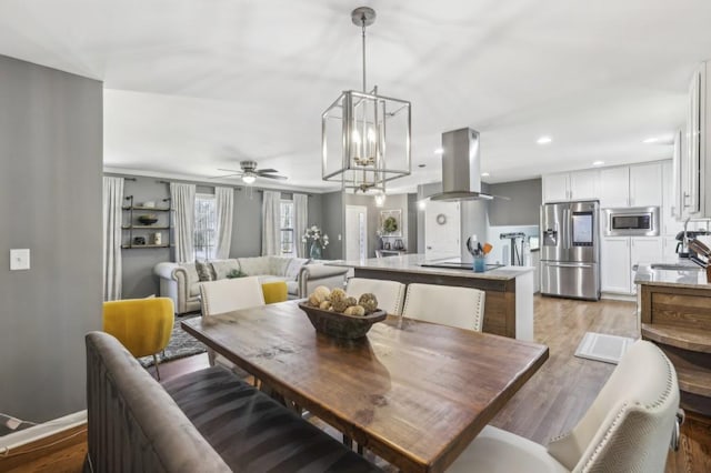 dining space with light wood-style floors, recessed lighting, and ceiling fan with notable chandelier